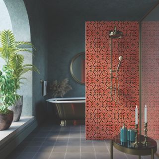 grey bathroom with decorative red tiled shower wall, grey floor tiles, metallic tub