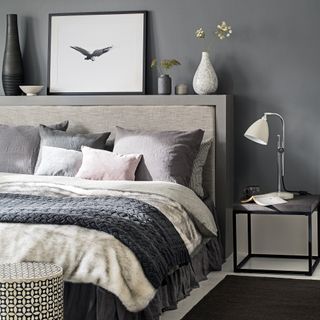 Grey bedroom with upholstered headboard and layered throws