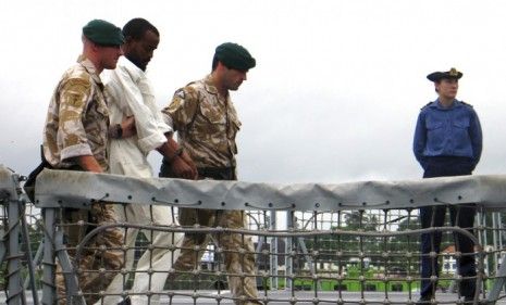 British Navy officials escort a suspected Somali pirate from a ship in April. The number of pirate attacks worldwide rose 10 percent in 2010.