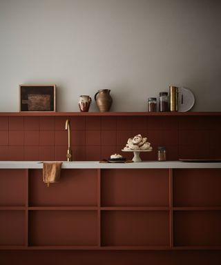 Little Greene terracotta kitchen with painted units and backsplash, shelf on top, white walls, white countertop,