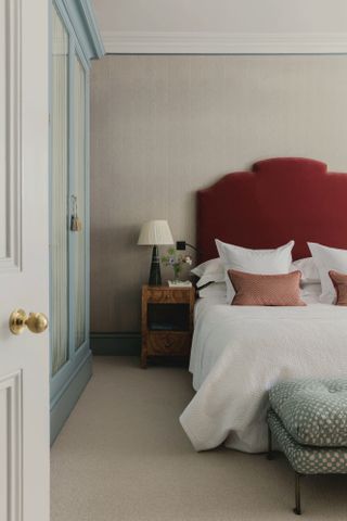 Bedroom with neutral walls, pale blue cupboards and bed with burgundy headboard
