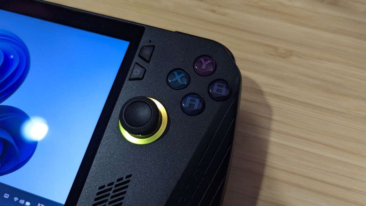 Asus ROG Ally X against a wood table with a focus on the face-buttons and analog stick on the right side.