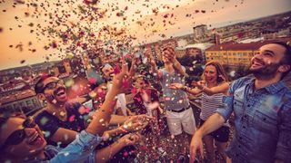 A group of friends celebrating on a rooftop, with confetti in the air