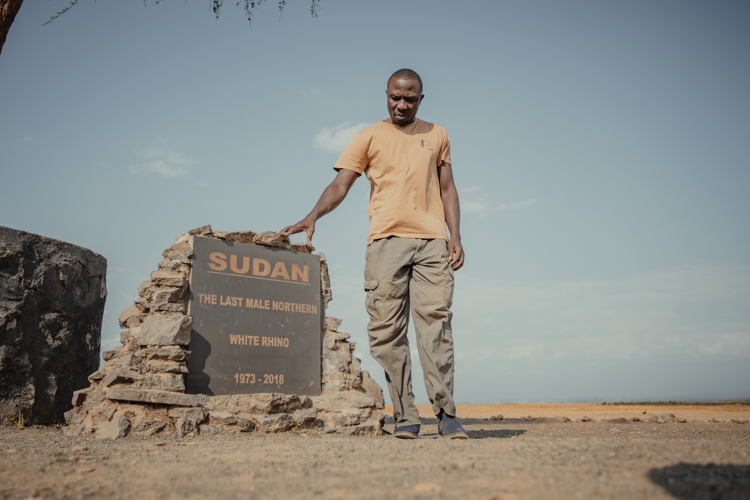man beside the "Sudan, the last male northern white rhino" memorial