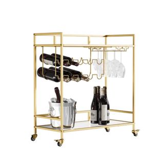 A gold bar cart with black bottles and glasses on it