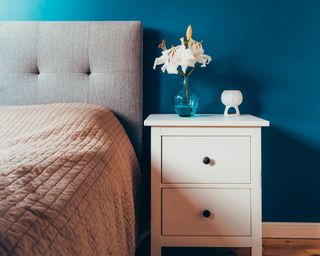 blue walls with a bed with an upholstered headboard and a white neat nightstand