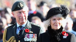 Prince Charles, Prince of Wales and Camilla, Duchess of Cornwall look on as veterans walk past during a Remembrance Day Service