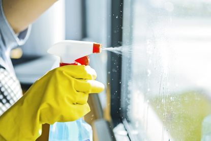 A woman cleaning a window with a microfiber cloth.