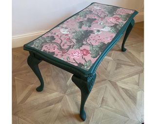 A coffee table upcycle with dark green paint decor and printed pink floral design