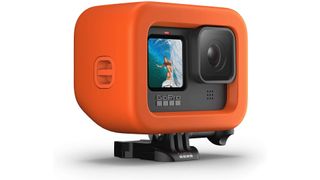 Bright orange GoPro Floaty housing surrounding a GoPro camera on a white background
