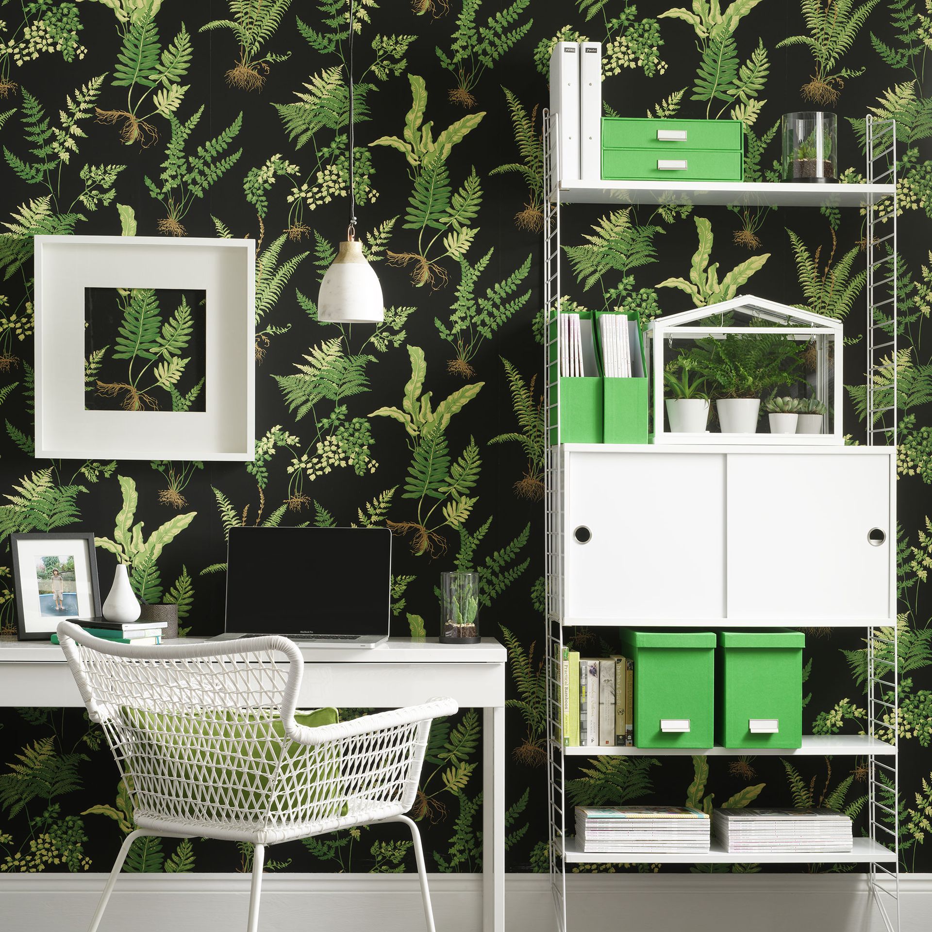 Home office with white desk and shelving unit in front of botanical wallpaper