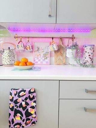A kitchen counter with LED lights and hanging mugs