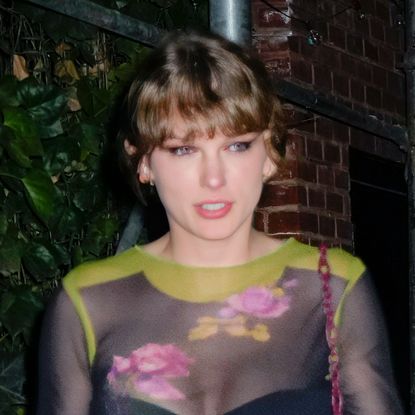Taylor Swift wears a sheer floral top and carries a red bag while on a date with Travis Kelce