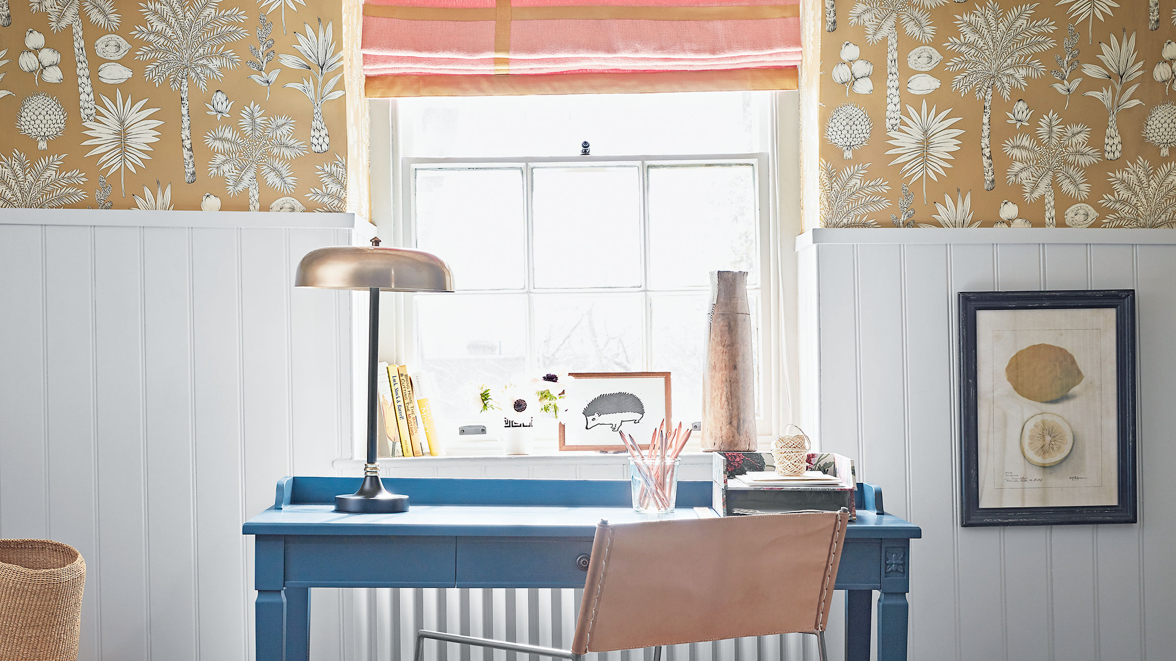 White panelling with patterned wallpaper with blue desk