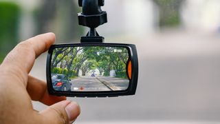 A hand adjusting the the position of a dash camera