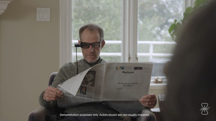 A person reading the newspaper wearing the camera glasses. Text on the image says &quot;demonstration purposes only. Actors shown are not visually impaired&quot;