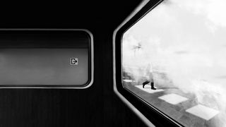 Black and white view through a train window with blurred figure walking outside