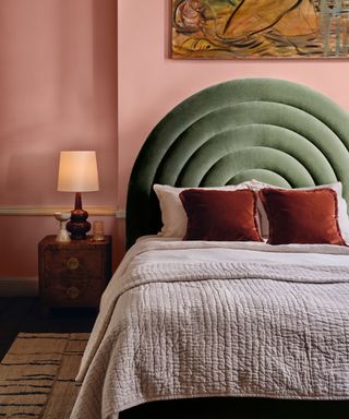 bedroom with pink wall, green curved headboard and textured bedding