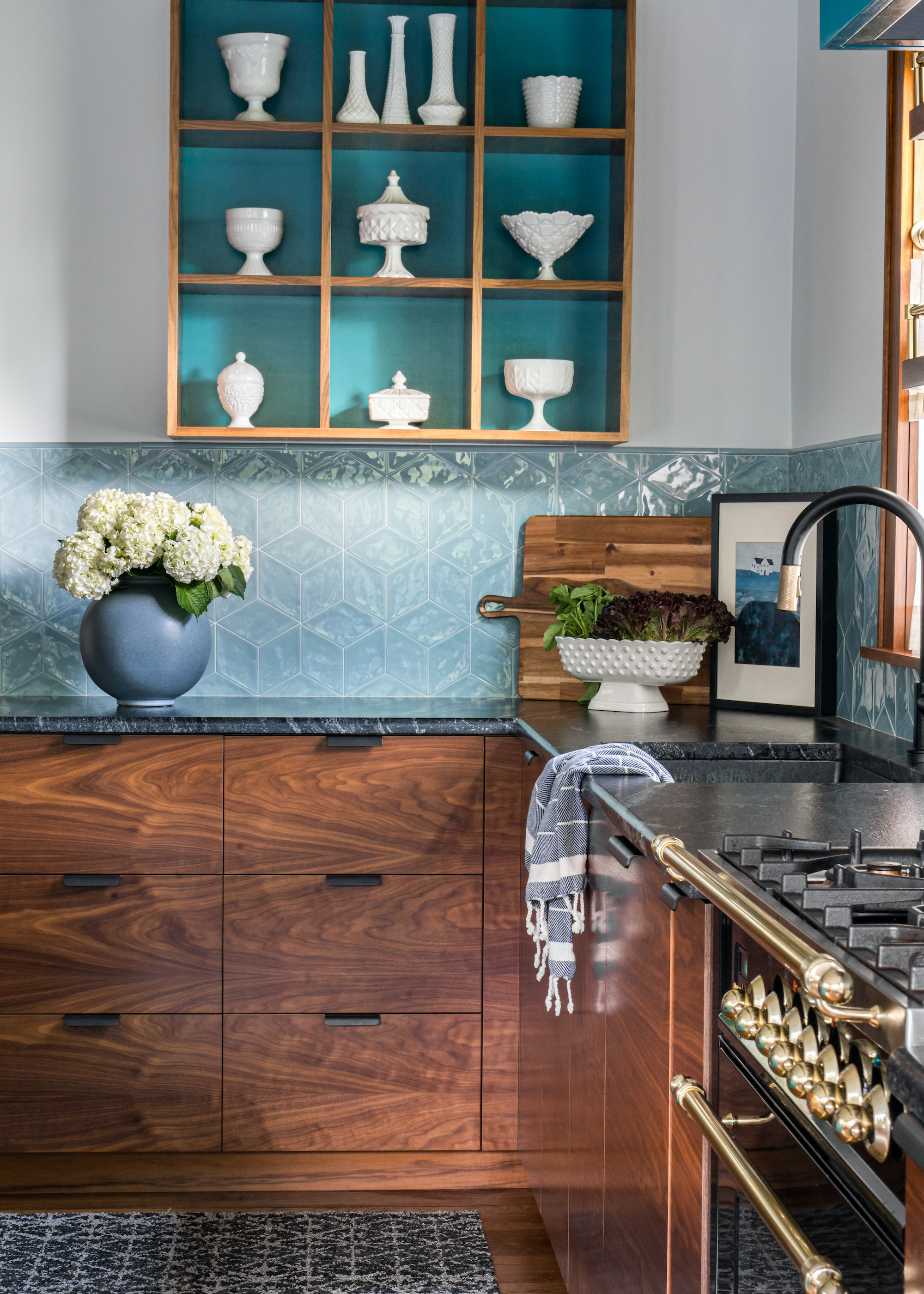 kitchen with wood units and square display cabinet backed in teal and dressed with white crockery