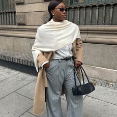 Nnenna Chem in a camel trench coat, white shawl, pinstripe trousers, and black handbag.