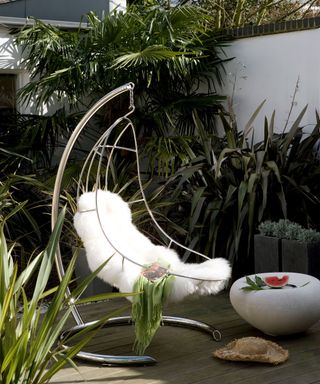 modern hanging chair on a deck surrounded by tropical planting