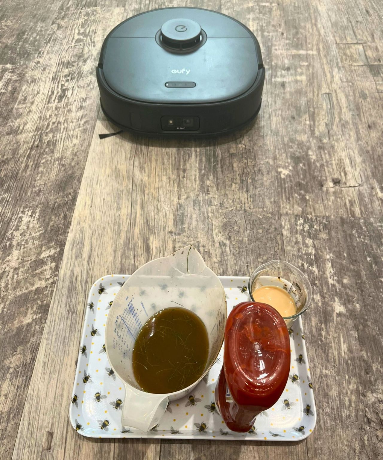 A tray with measuring jugs of ketchup, muddy water and milky coffee