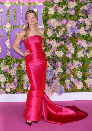 A photo of Renée Zellweger posing in a strapless hot pink vintage Balmain gown with a train.