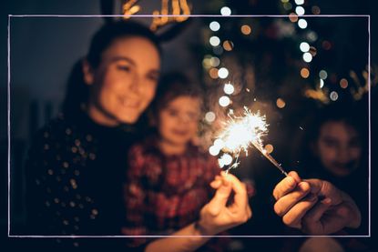 A close up of a sparkler on Bonfire Night with faces in the background