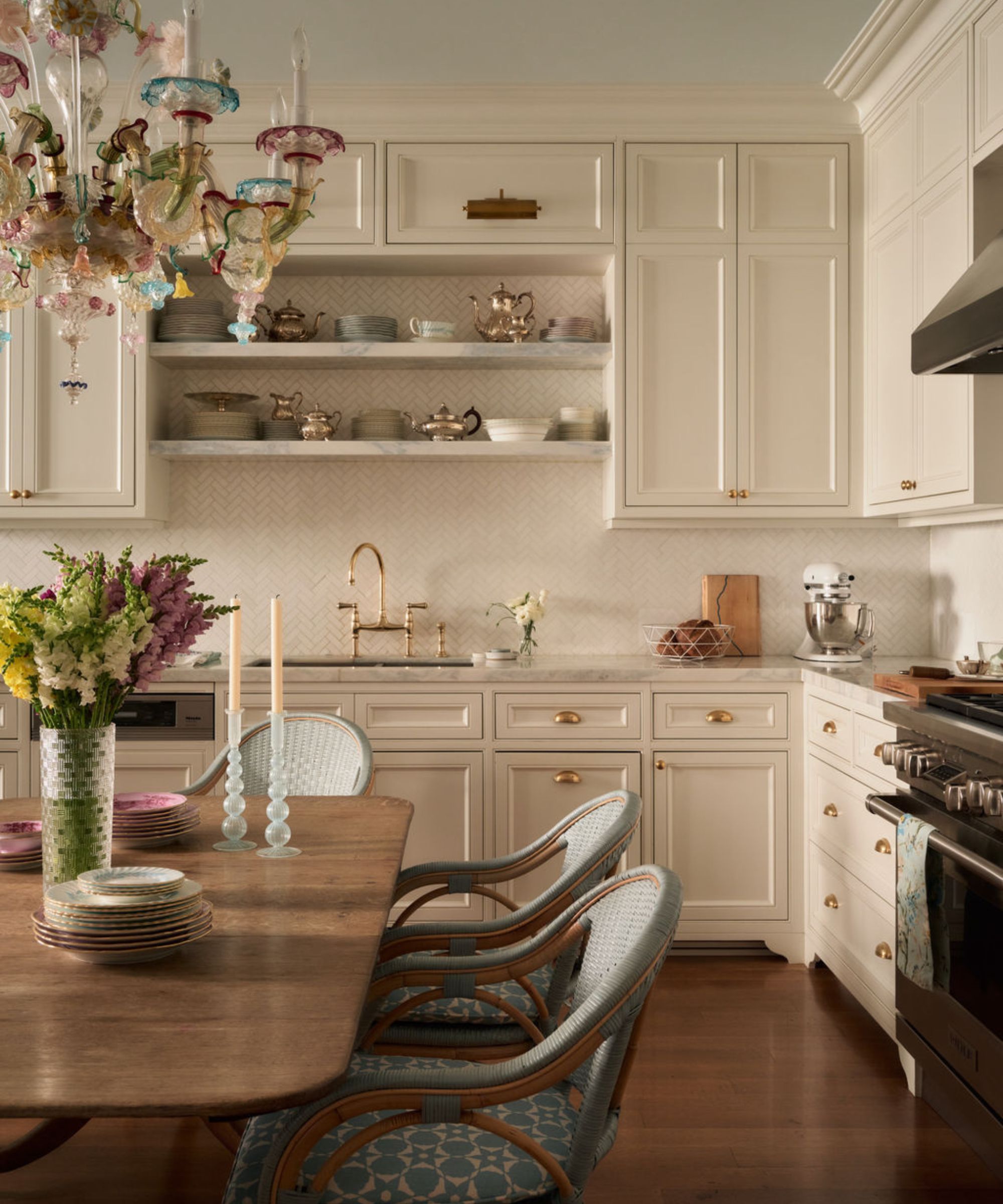 a neutral layered kitchen with traditional cabinetry, a light blue painted ceiling, murano chandelier and antique table and chairs