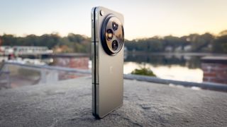 OnePlus Open plié sur un piédestal avec le lever du soleil derrière lui