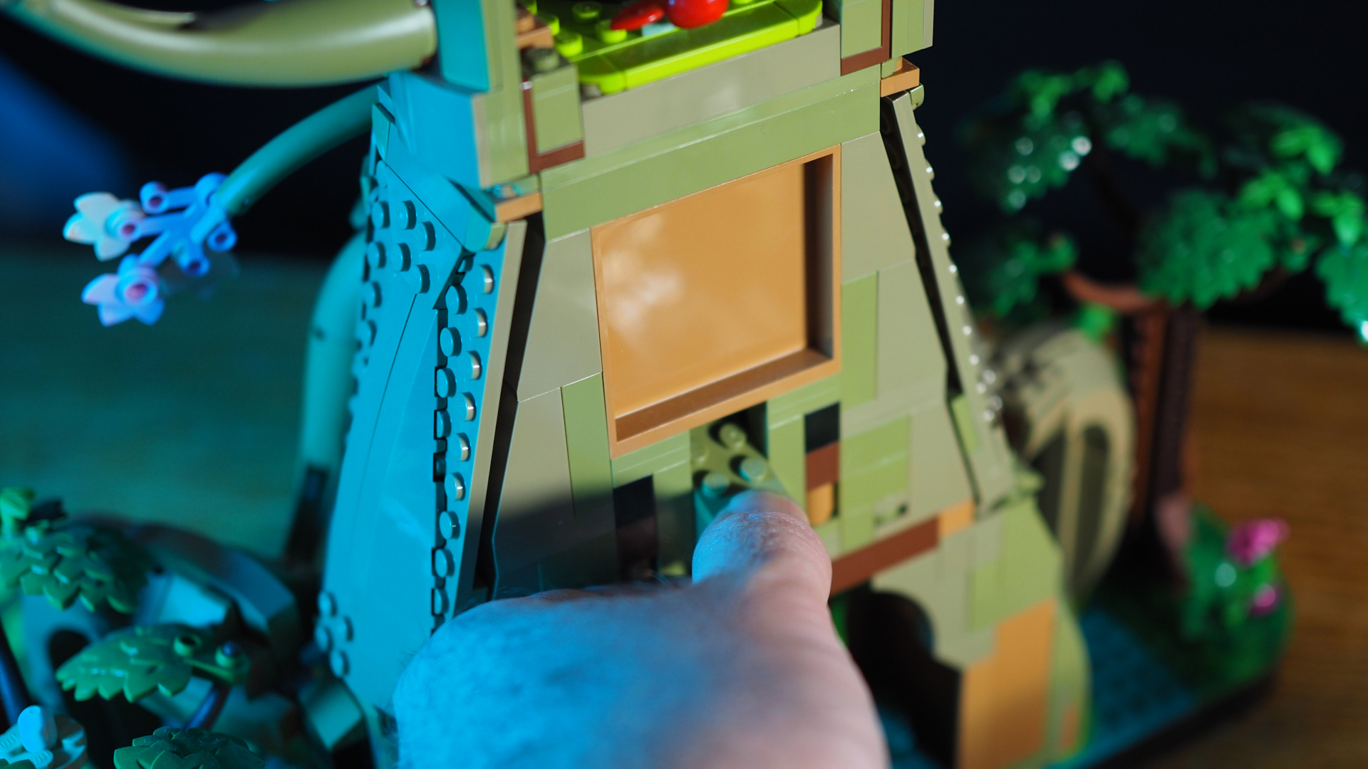 A hand presses a brick down in the back of the Lego Great Deku Tree