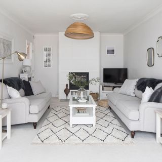 Living room with white walls, light grey sofas and geometric rug