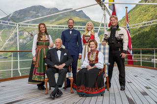 Crown Princess Ingrid Alexandra, King Harald, Queen Sonja, Prince Sverre Magnus, Crown Prince haakon, Crown Princess Mette-Marit on a boat with mountains in the background