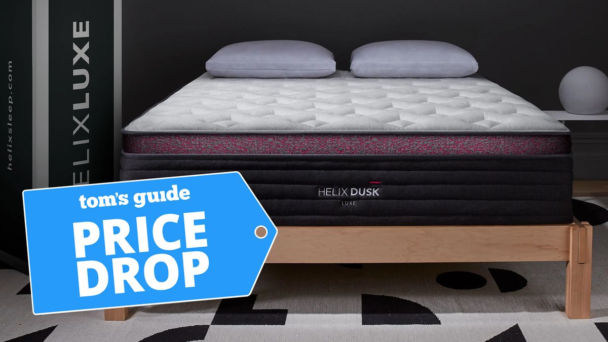 The Helix Dusk Luxe Mattress on a bed frame in a showroom next to a box, a Tom&#039;s Guide price drop deals graphic (left)