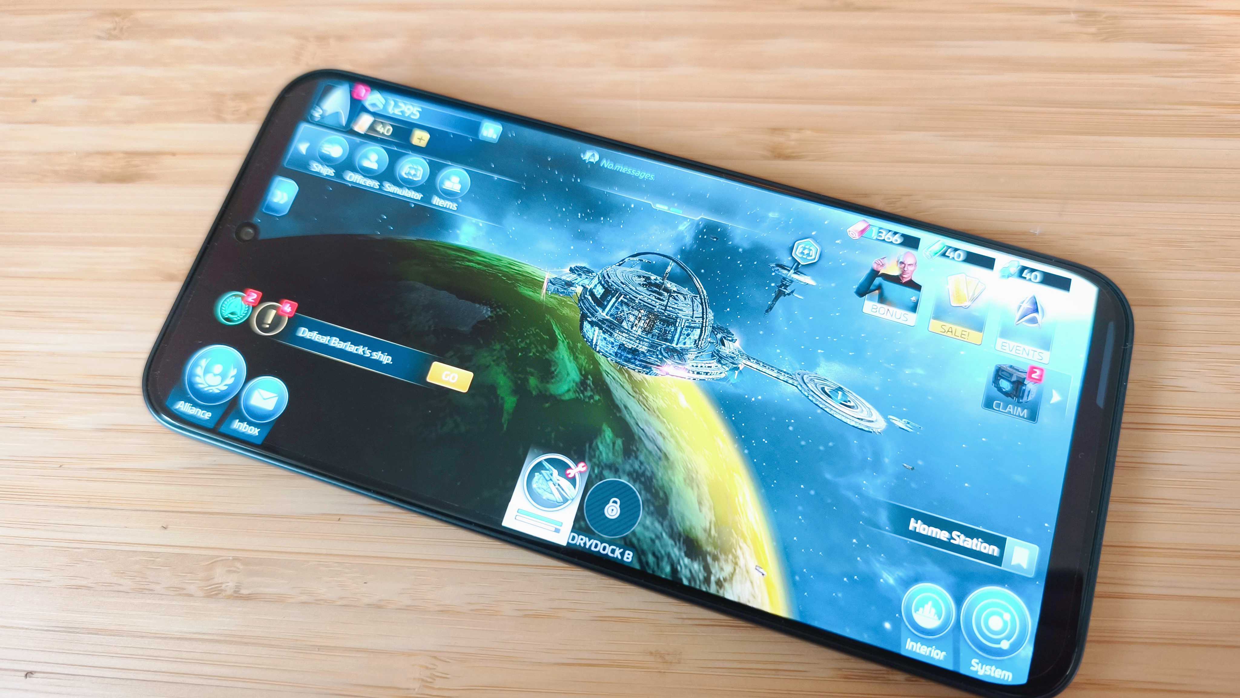 A black Infinix GT 30 Pro phone on a wooden desk