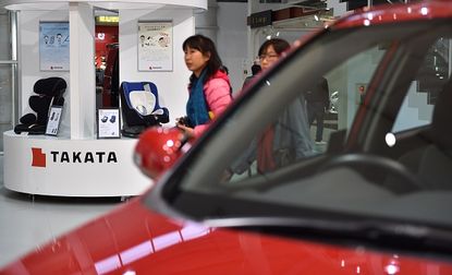 Visitors look at a display of Takata auto parts