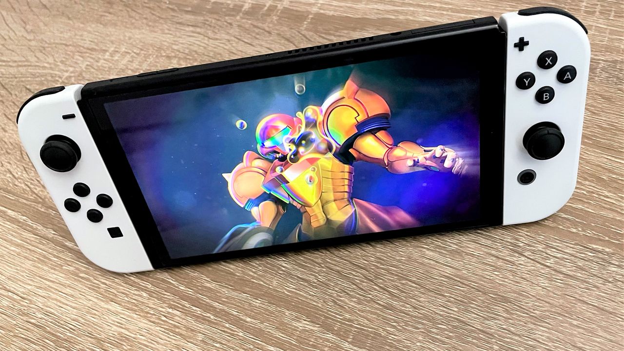 Nintendo Switch OLED on wooden surface, with Metroid Dread on the screen