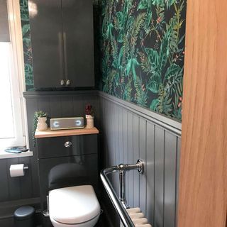 Bathroom with wallpaper on wall and black cabinet