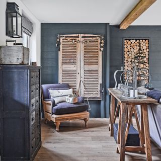 dark walled room with armchair and feature wall of logs