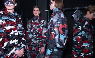 Group of male models in blue, grey, white and red camo outfits and camo face paint