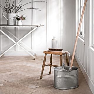 cleaning material with wooden table and modern mop and bucket