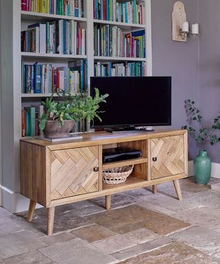 TV on a wooden unit by bookshelves