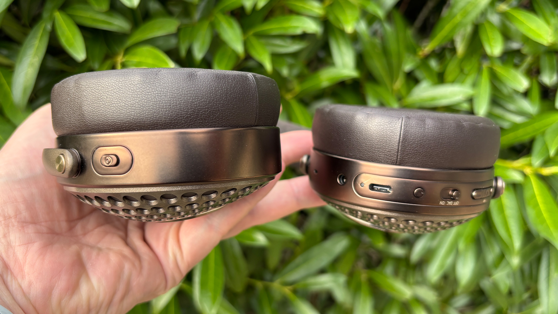 Focal Bathys MG wireless headphones held in hand showing earcup controls and connection