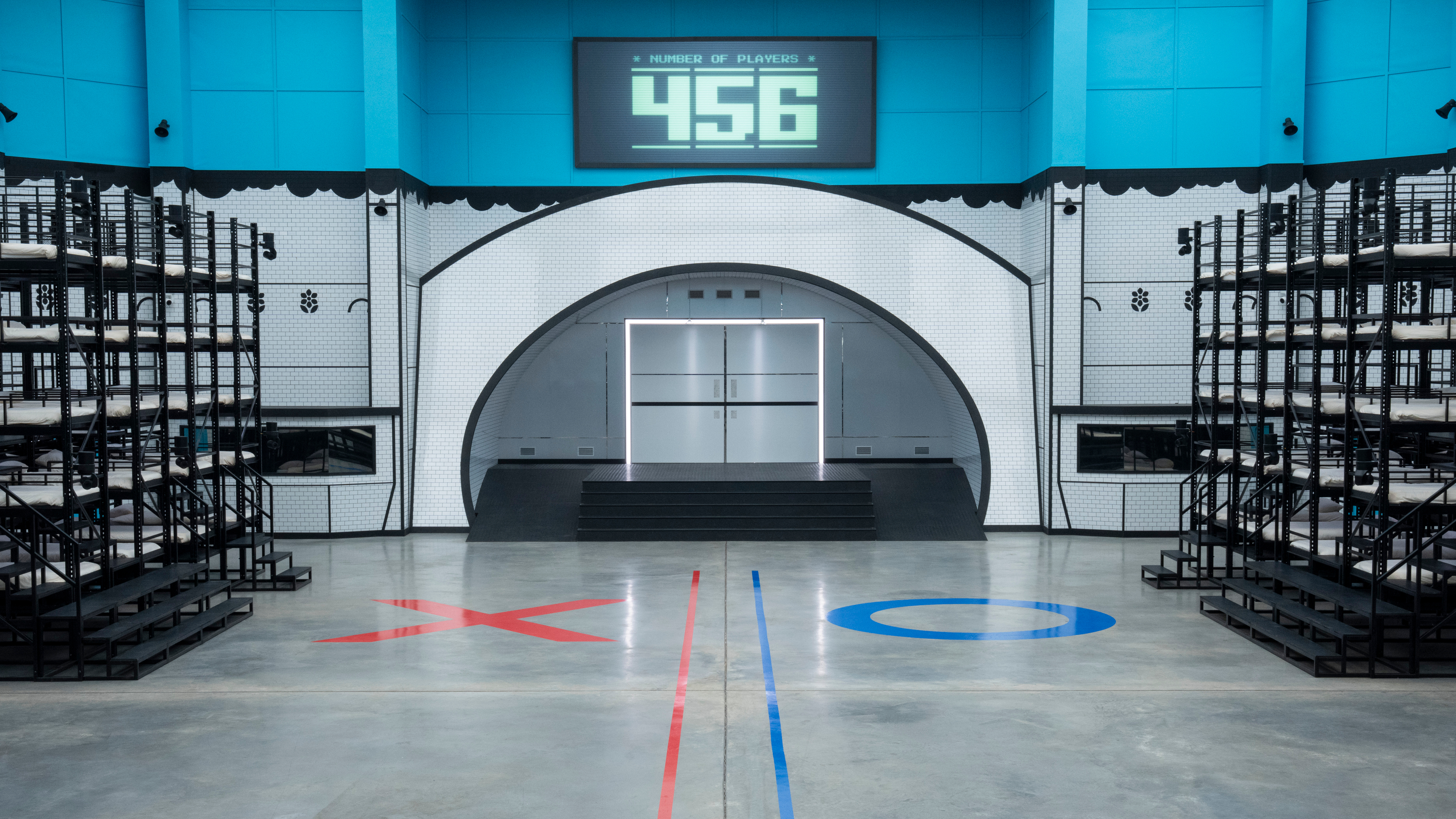 A "Squid Game: The Challenge" season 2 first-look still showing the empty holding room, bunkbeds with X & O sides painted on the floor
