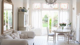 White living room with all white furniture and white painted floorboards to show how to make a room look bigger with paint