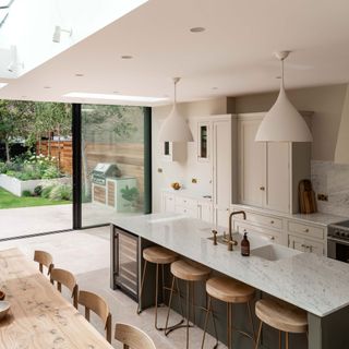 open plan kitchen diner with kitchen island and bar stools and a skylight and sliding doors leading out into the garden wine fridge