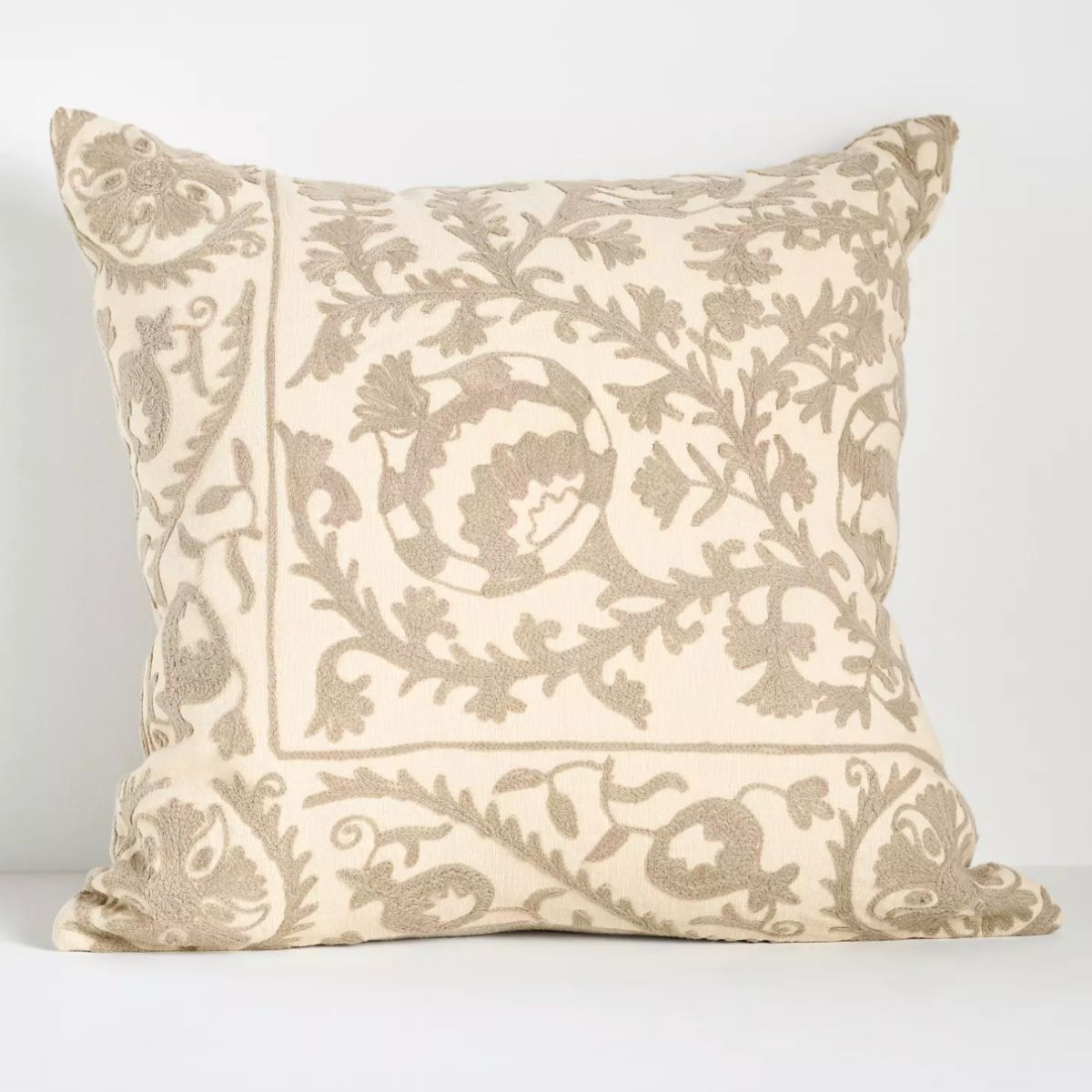 A neutral cushion with neutral embroidered floral design