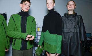 Three models - two with green and black jumpers, and one with a black coat