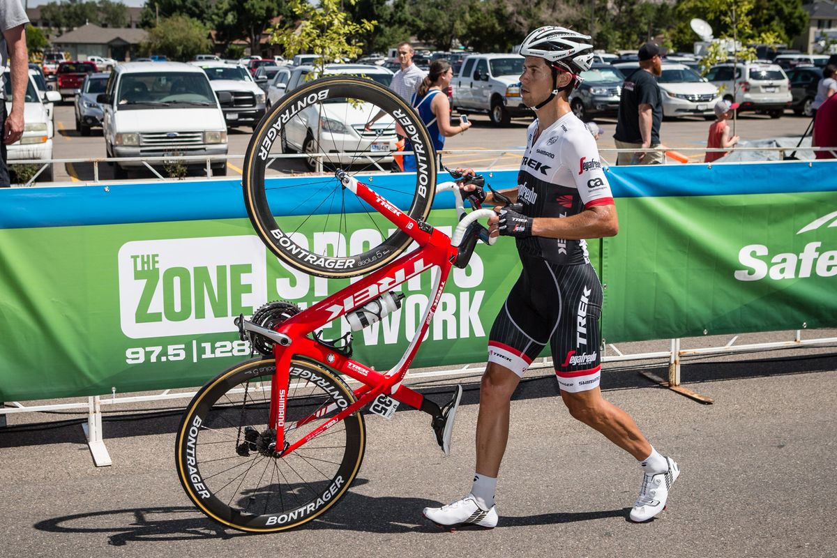 Kiel Reijnen walks his bike across the line during stage 1 of the Tour of Utah after contact with another rider left his front wheel inoperable.