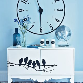 blue wall with clock and white vanity with birds sticker